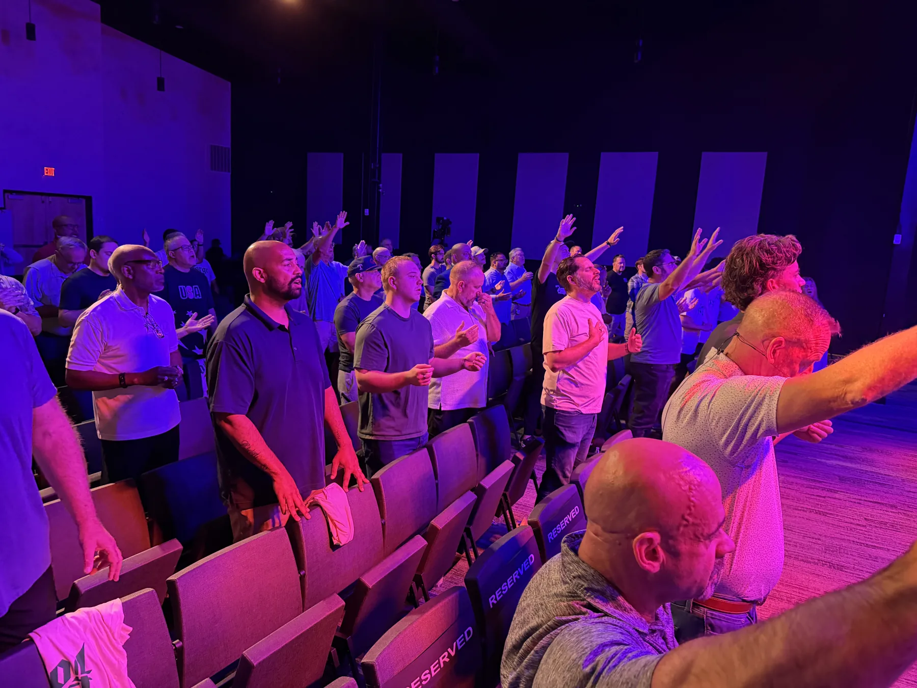 Worship fills the room under purple and orange stage lights
