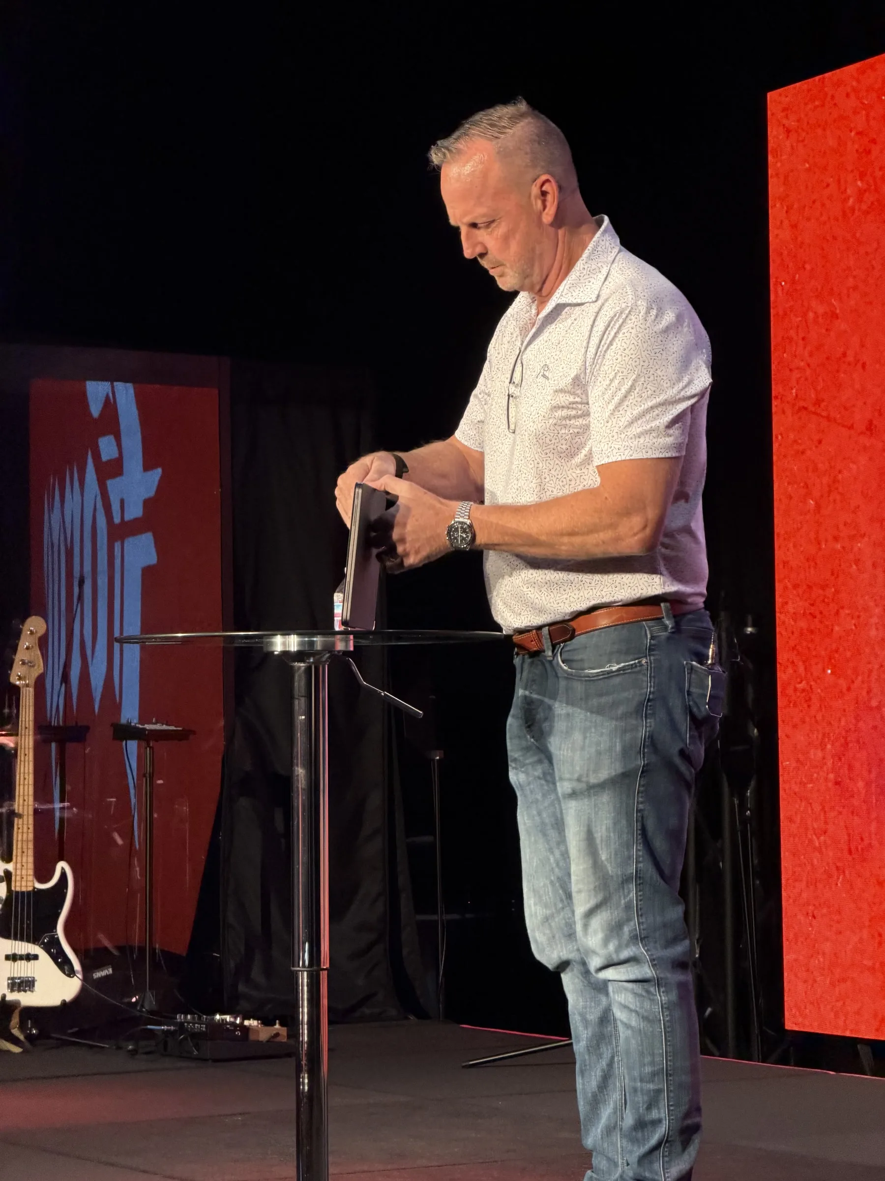 A speaker stands at a microphone on the Forge One Day stage