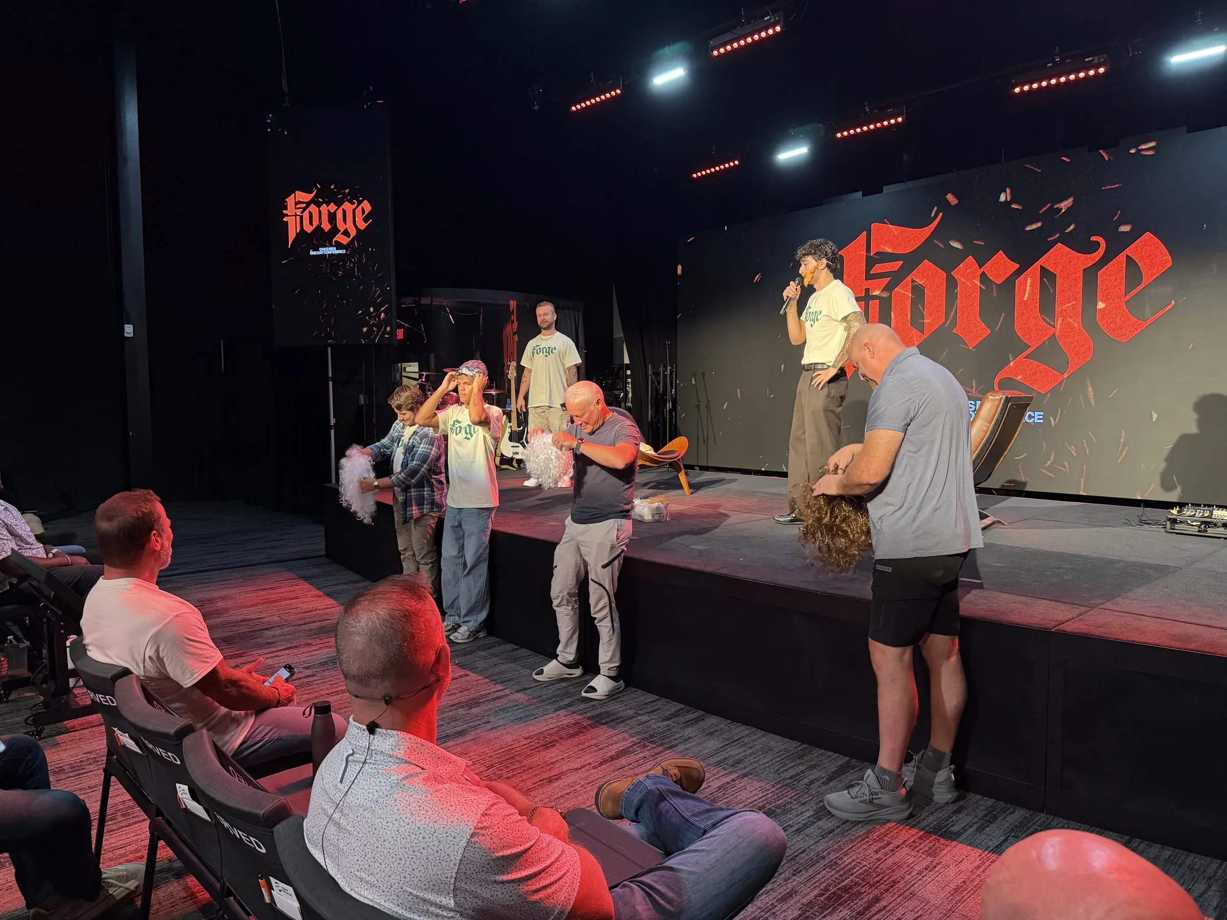 Several men gather with a speaker at the front of the Forge One Day stage