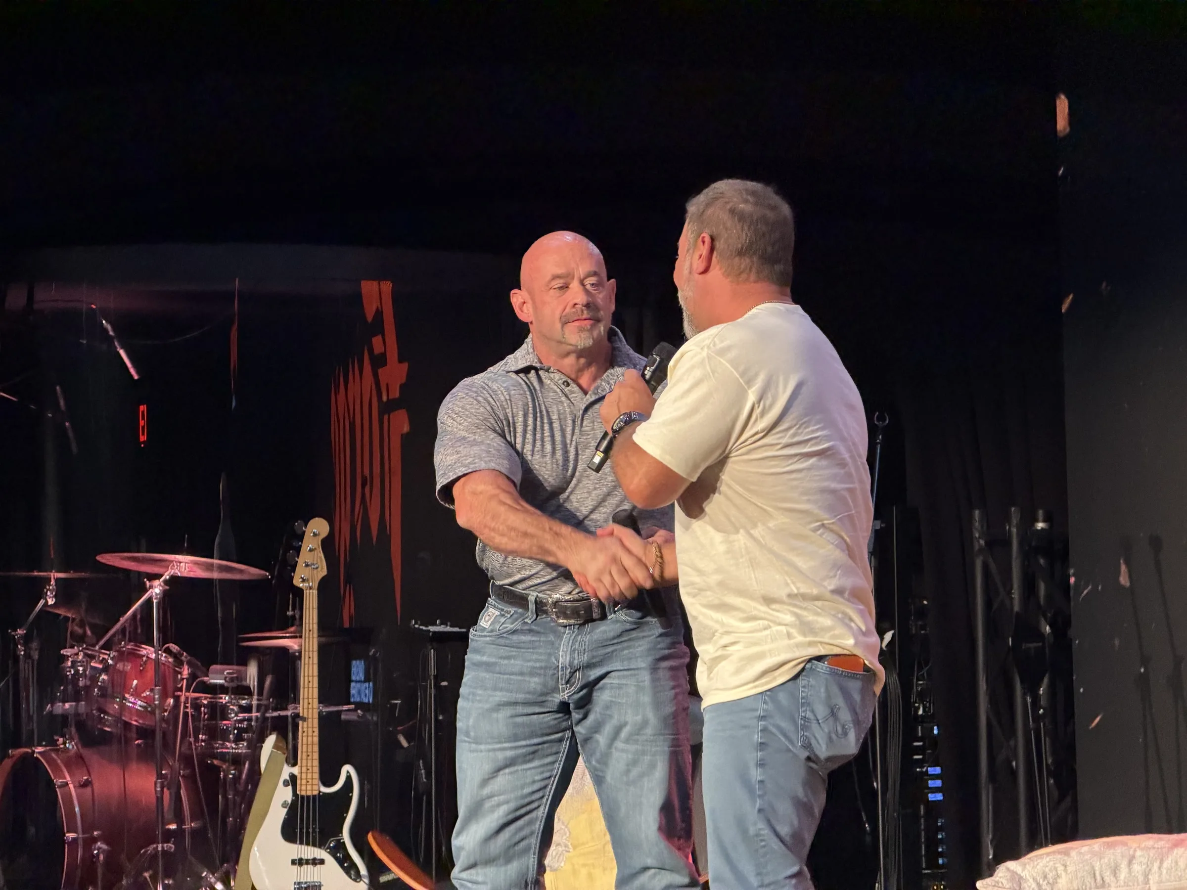 Two men embrace beside the Forge One Day stage