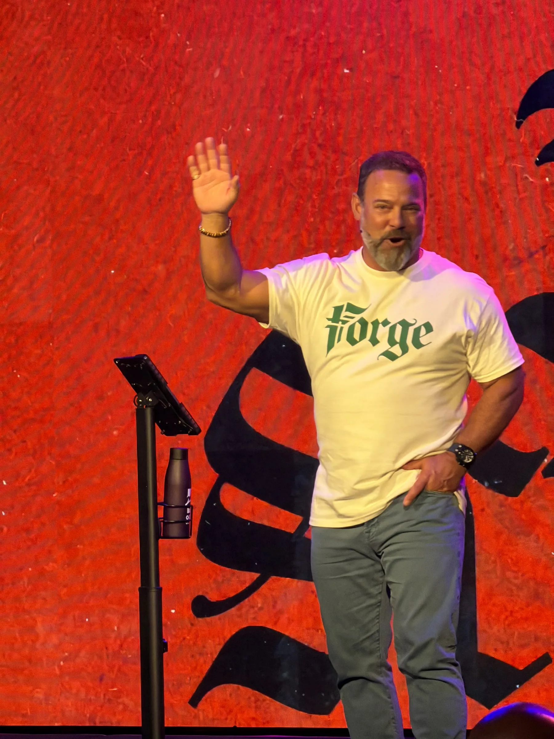 A speaker raises his hand in front of the red Forge backdrop